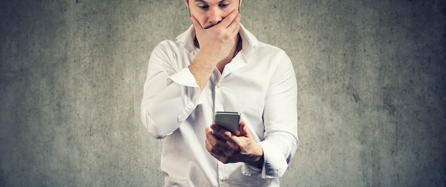 Shocked man watching smartphone having problem Mann sieht besorgt auf sein Handy